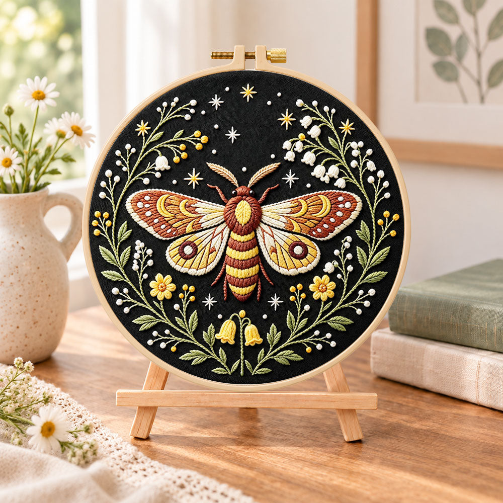 Starry night moth embroidery kit finished hoop displayed on a wooden stand as cosy tabletop decor