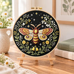 Starry night moth embroidery kit finished hoop displayed on a wooden stand as cosy tabletop decor