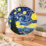 Starry night sky embroidery kit finished hoop displayed on a wooden stand as cozy tabletop decor
