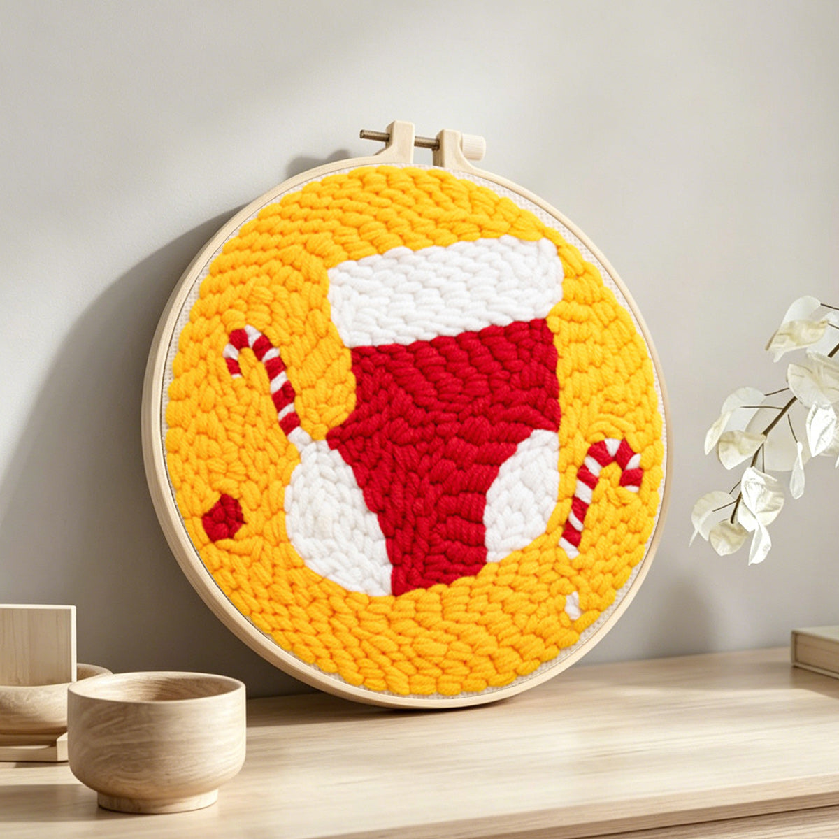 Stocking and candy canes punch needle artwork displayed on a table