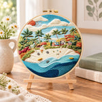 Sunny tropical beach embroidery kit finished hoop displayed on a wooden stand as cosy tabletop decor