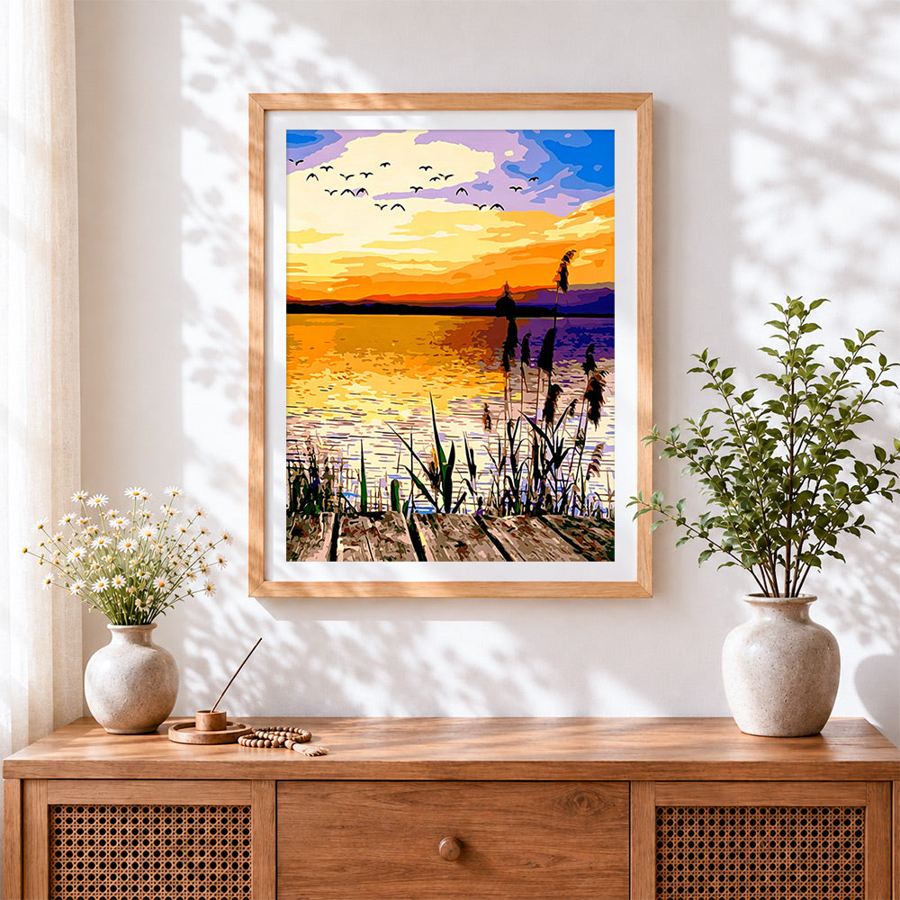 Finished sunset over water with flying birds cross stitch artwork displayed