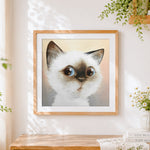 Finished surprised cat face cross stitch artwork displayed
