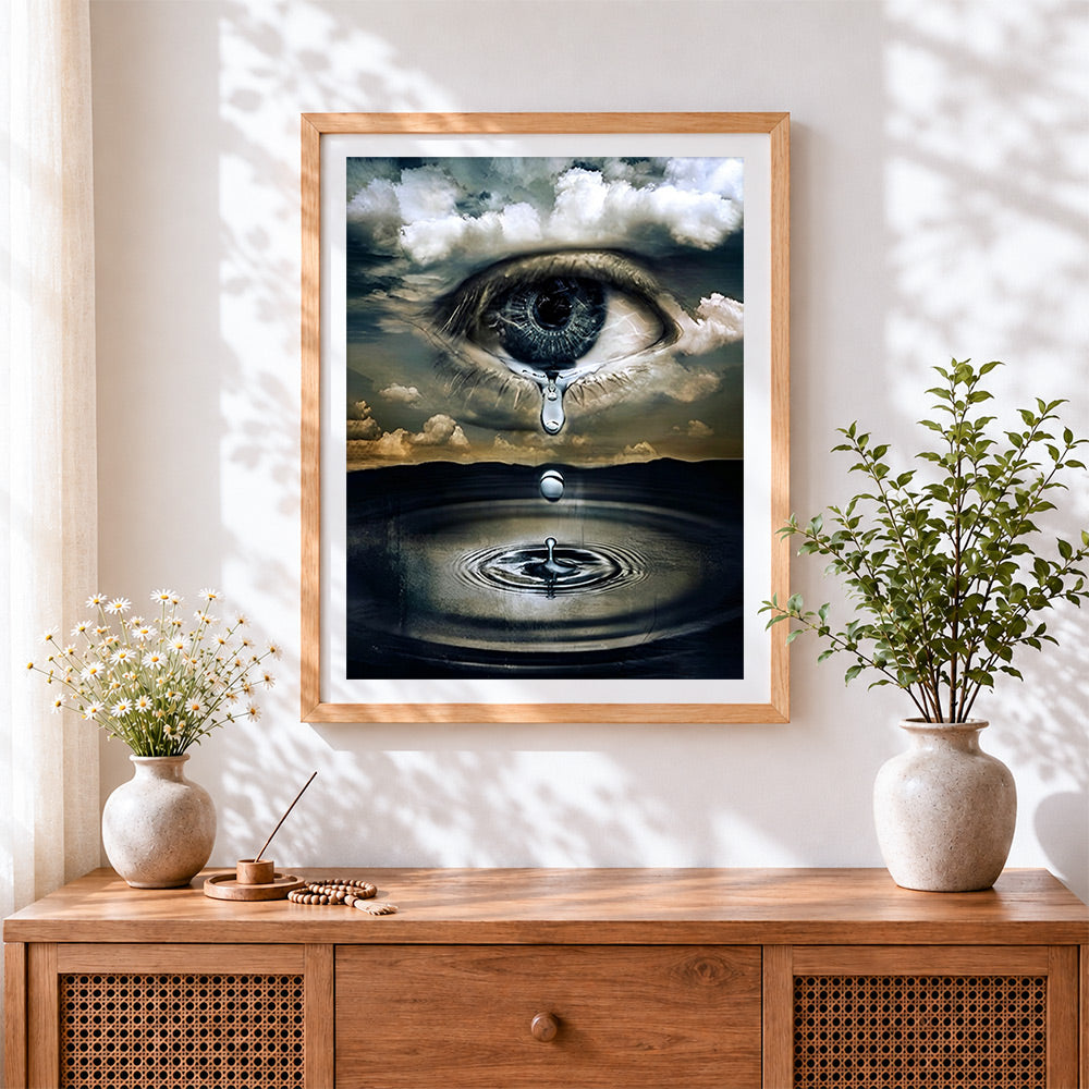 Finished surreal eye in clouds with tear cross stitch artwork displayed