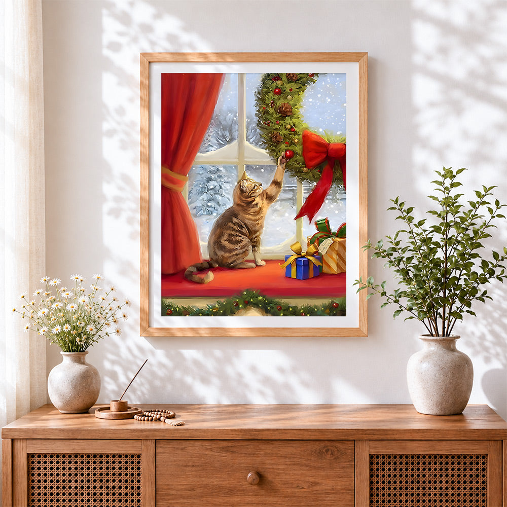 Finished tabby cat playing with a christmas wreath cross stitch artwork displayed