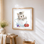 Tabby kitten in teacup with fruit cross stitch artwork displayed on wall as home decor