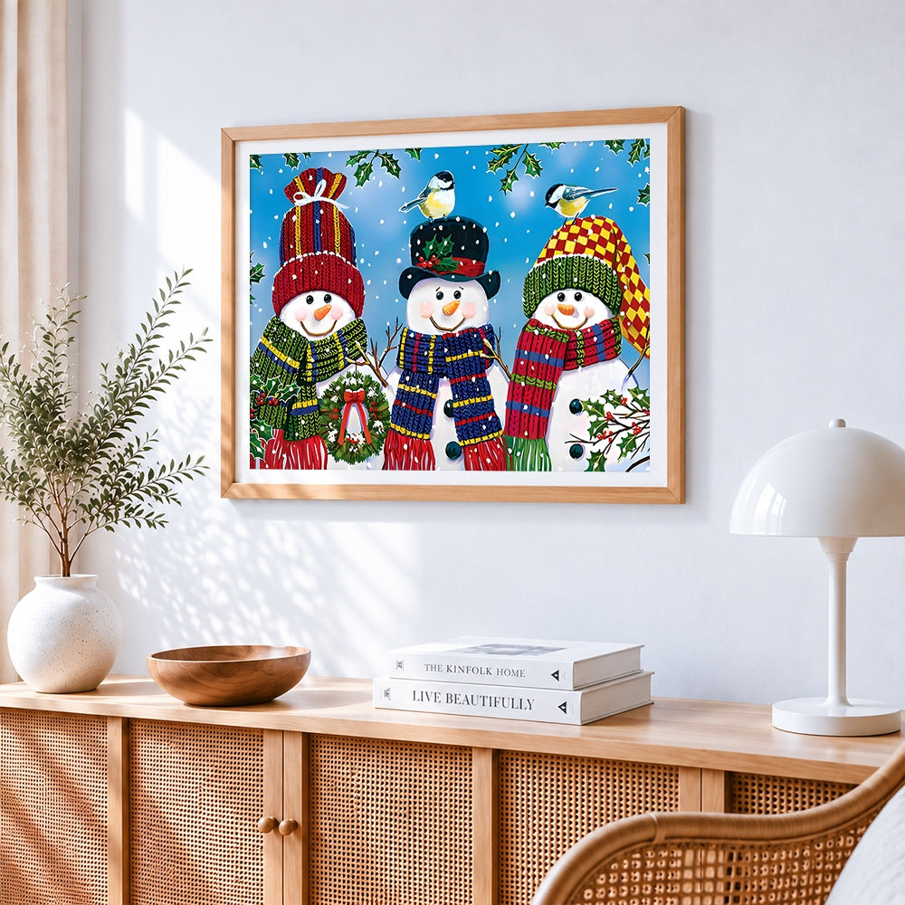 Three cheerful snowmen in knitted hats paint by numbers artwork displayed on wall as home decor