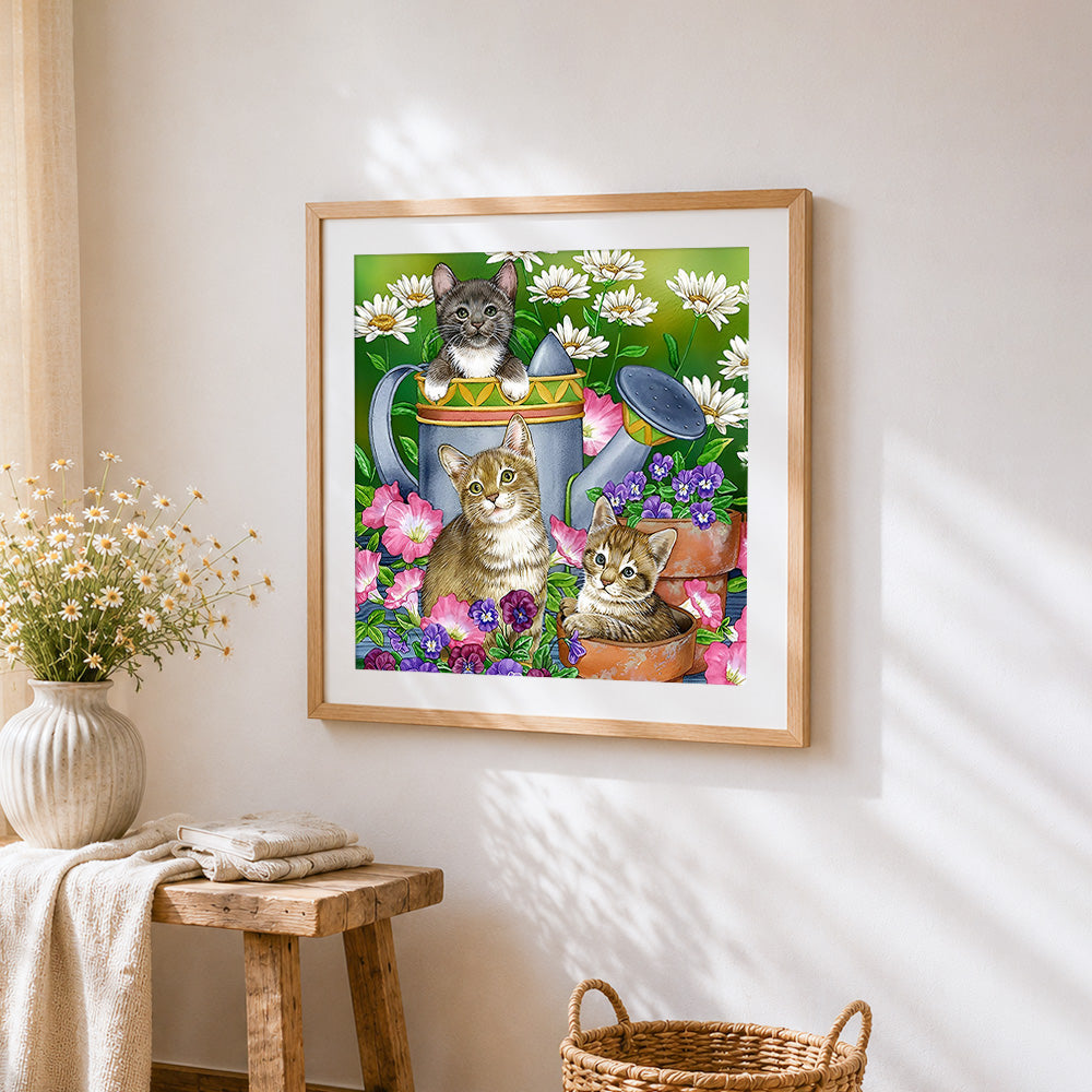 Three kittens in garden watering can cross stitch artwork displayed on wall as home decor