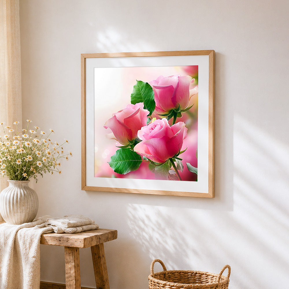 Three pink roses cross stitch artwork displayed on wall as home decor