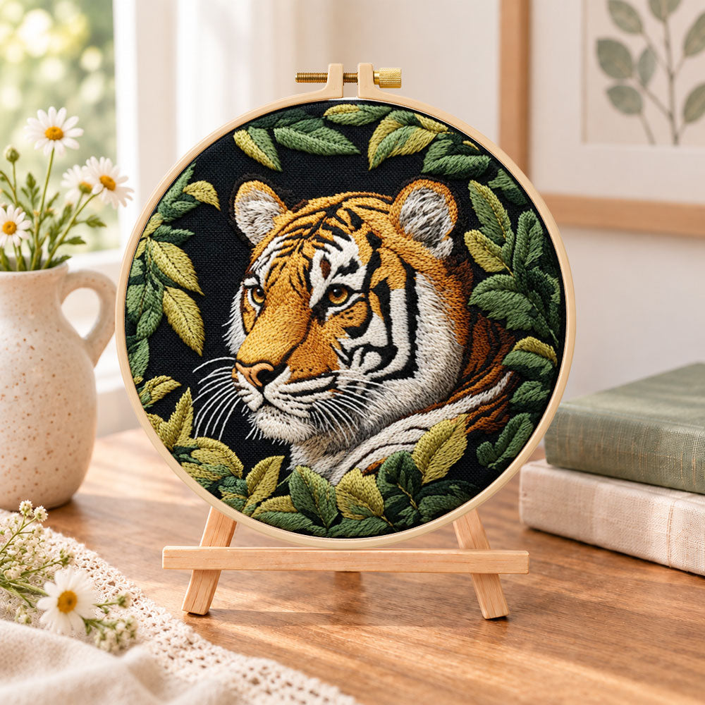 Tiger among green leaves embroidery kit finished hoop displayed on a wooden stand as cosy tabletop decor