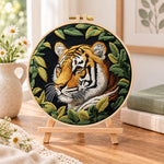 Tiger among green leaves embroidery kit finished hoop displayed on a wooden stand as cosy tabletop decor