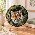Tiger in dark foliage embroidery kit finished hoop displayed on a wooden stand as cosy tabletop decor