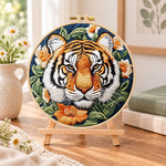 Tiger surrounded by blooms embroidery kit finished hoop displayed on a wooden stand as cosy tabletop decor
