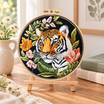 Tiger with wild blooms embroidery kit finished hoop displayed on a wooden stand as cosy tabletop decor