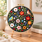 Titmouse and colourful wildflowers embroidery kit finished hoop displayed on a wooden stand as cosy tabletop decor