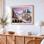 Traditional snowy village and church cross stitch artwork displayed on wall as home decor