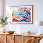 Two birds on a cherry blossom branch cross stitch artwork displayed on wall as home decor