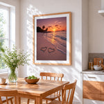 Two hearts in the sand at sunset cross stitch artwork displayed on wall as home decor