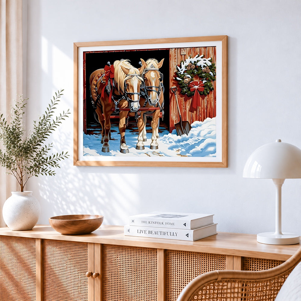 Two horses in the snow with christmas wreath cross stitch artwork displayed on wall as home decor
