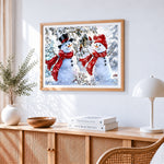 Two snowmen with birdhouse cross stitch artwork displayed on wall as home decor