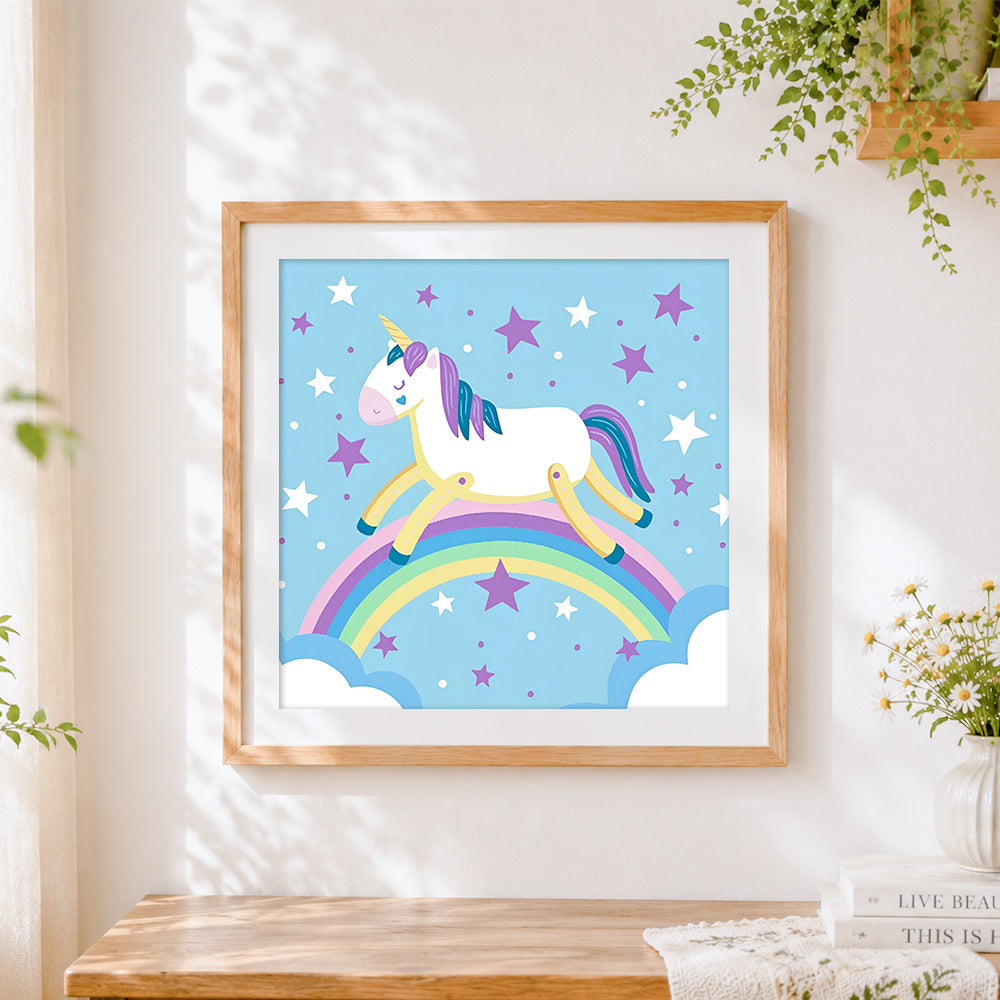 Finished unicorn balancing on a rainbow cross stitch artwork displayed