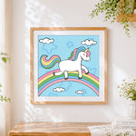 Finished unicorn walking on a rainbow cross stitch artwork displayed