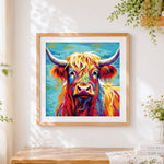 Finished vibrant highland cow on blue background cross stitch artwork displayed