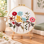 Vibrant mixed blooms embroidery kit finished hoop displayed on a wooden stand as cozy tabletop decor