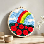 Vibrant rainbow with red roses punch needle artwork displayed on a table