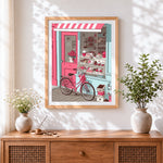 Finished vintage bicycle and pink bakery cross stitch artwork displayed