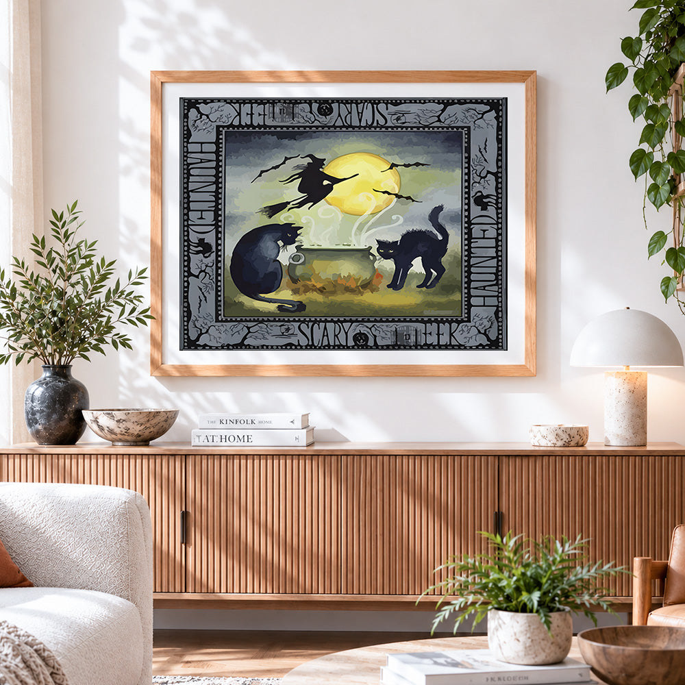 Finished vintage haunted halloween cauldron with black cats cross stitch artwork displayed