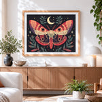 Finished vintage style moth and moon cross stitch artwork displayed