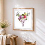 Watercolour deer skull with bird and flowers cross stitch artwork displayed on wall as home decor
