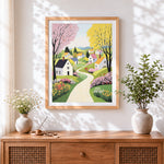 Finished whimsical colourful cottages and flower path cross stitch artwork displayed