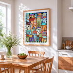 Whimsical colourful village cross stitch artwork displayed on wall as home decor
