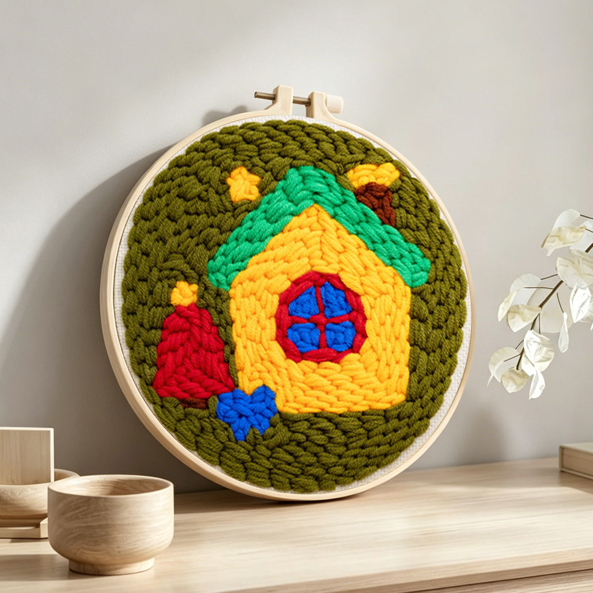 Whimsical fairy house punch needle artwork displayed on a table