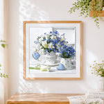 Finished white and blue floral still life cross stitch artwork displayed
