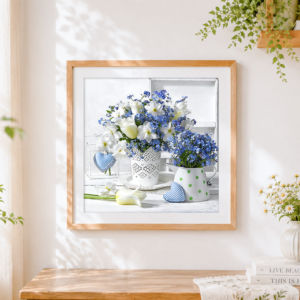 Finished white and blue floral still life cross stitch artwork displayed