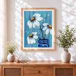 Finished white daisies in blue vase cross stitch artwork displayed