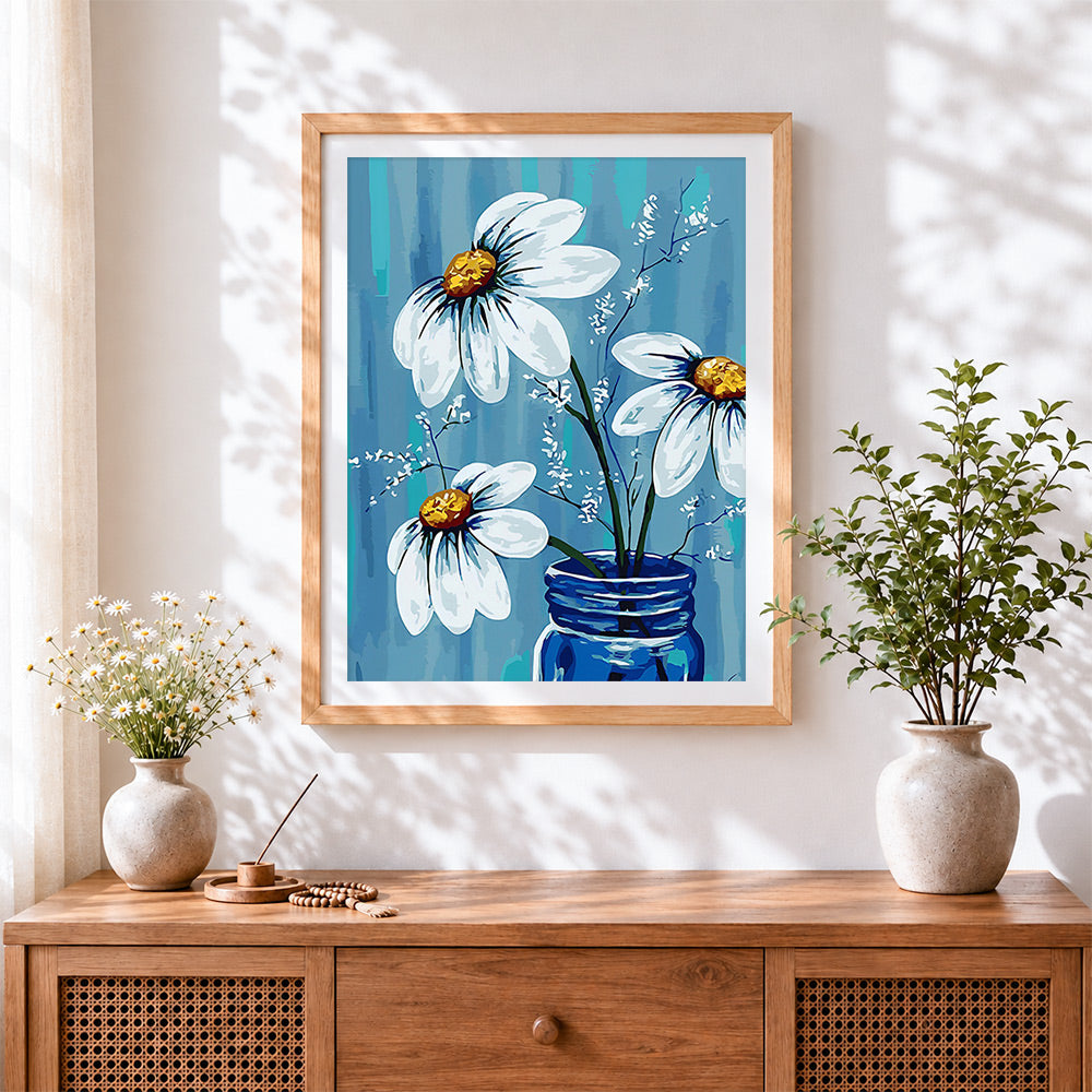 Finished white daisies in blue vase cross stitch artwork displayed