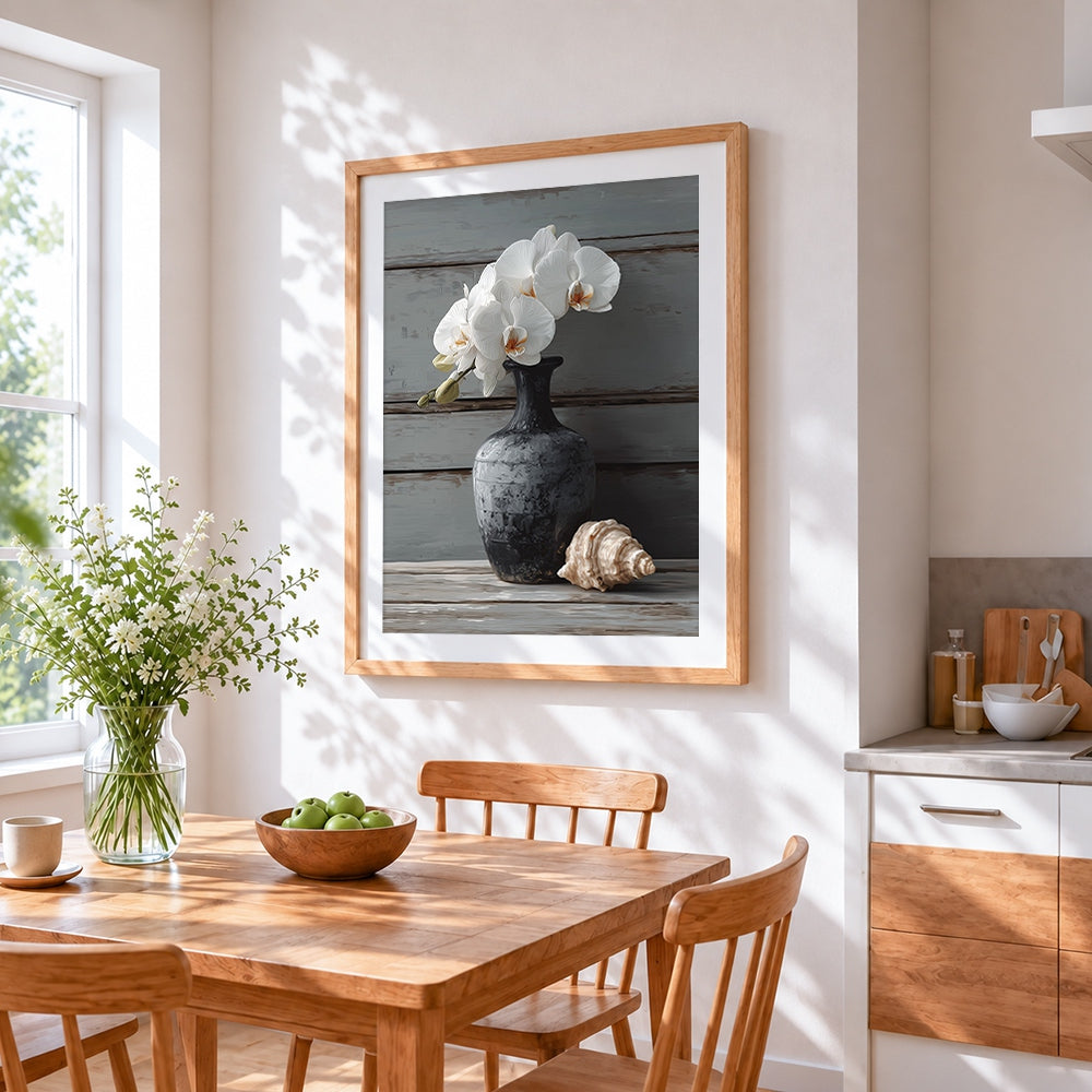 White orchids in a dark vase with shell cross stitch artwork displayed on wall as home decor