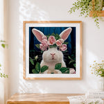 Finished white rabbit with pink rose crown cross stitch artwork displayed
