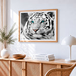 White tiger with blue eyes cross stitch artwork displayed on wall as home decor