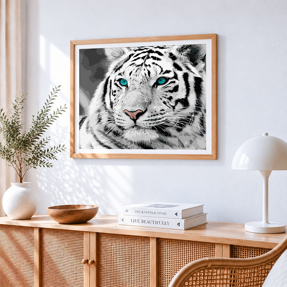 White tiger with blue eyes cross stitch artwork displayed on wall as home decor