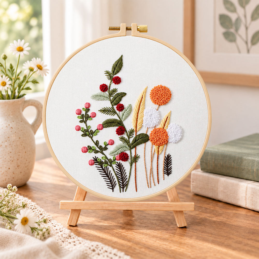 Wild berry and dandelion blooms embroidery kit finished hoop displayed on a wooden stand as cosy tabletop decor