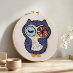 Winking owl punch needle artwork displayed on a table