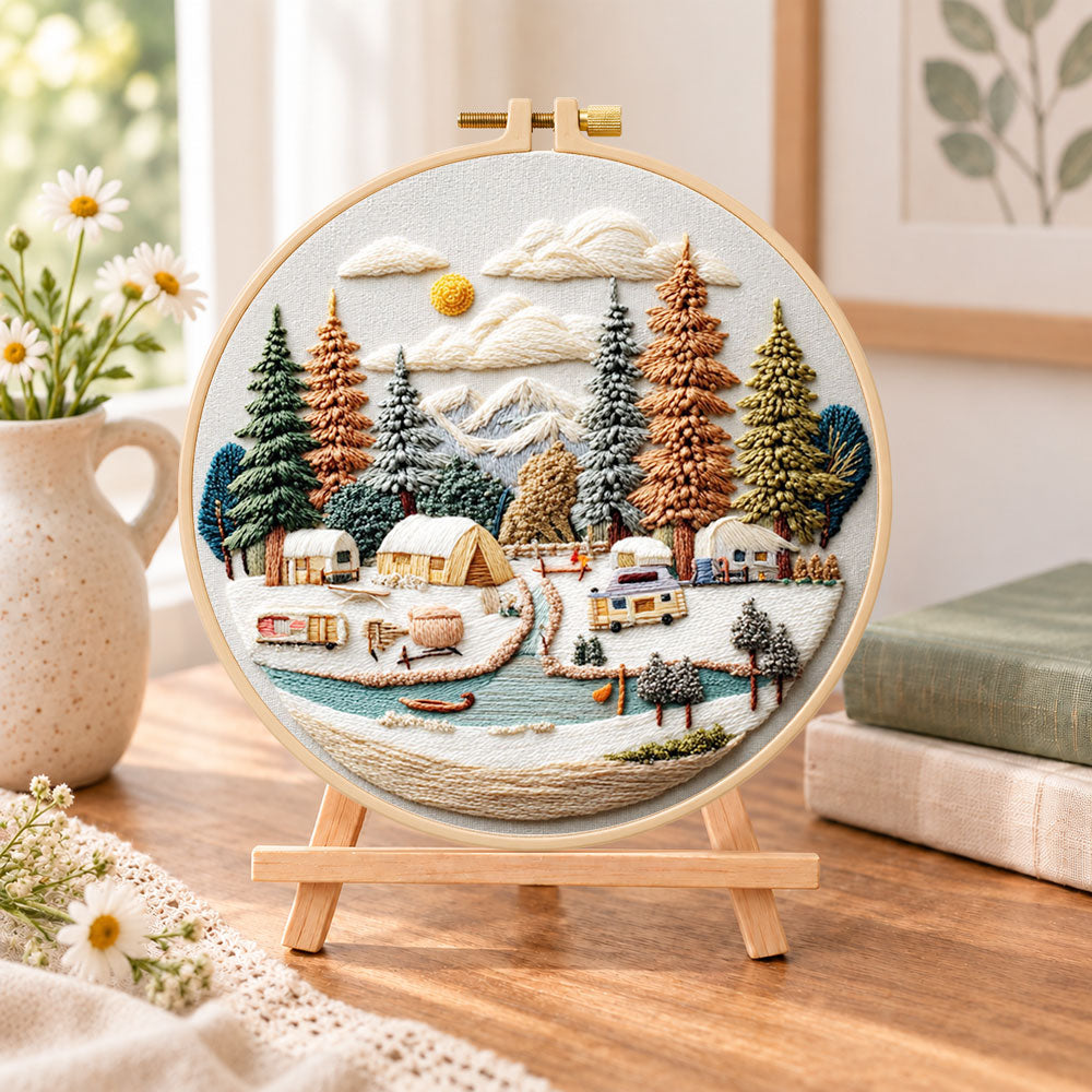 Winter camping valley embroidery kit finished hoop displayed on a wooden stand as cosy tabletop decor