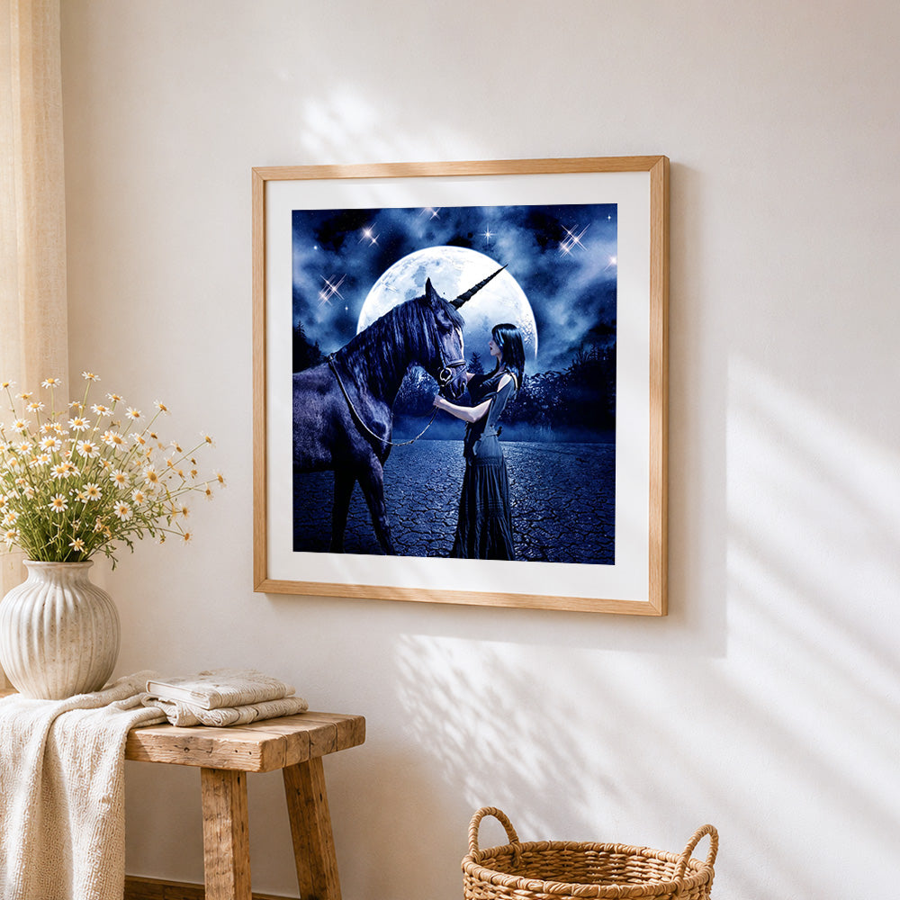 Woman and dark unicorn under a full moon cross stitch artwork displayed on wall as home decor