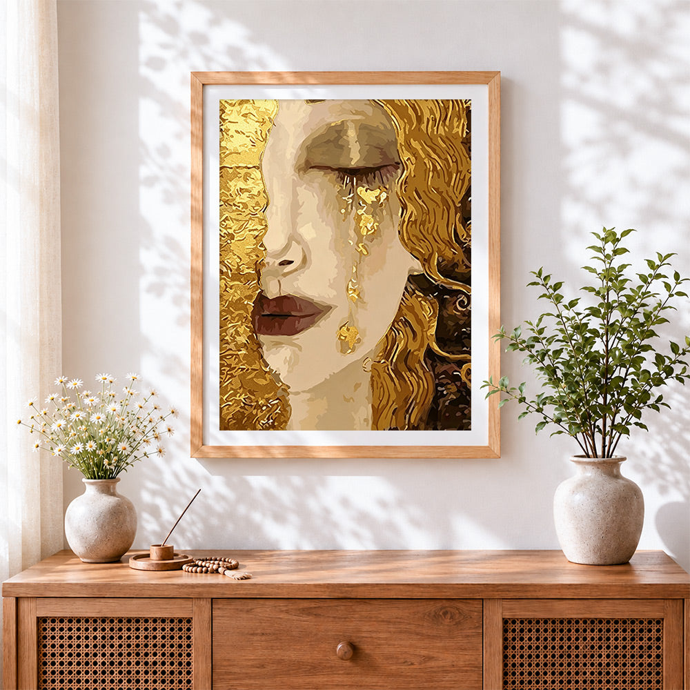 Finished woman crying golden tears cross stitch artwork displayed