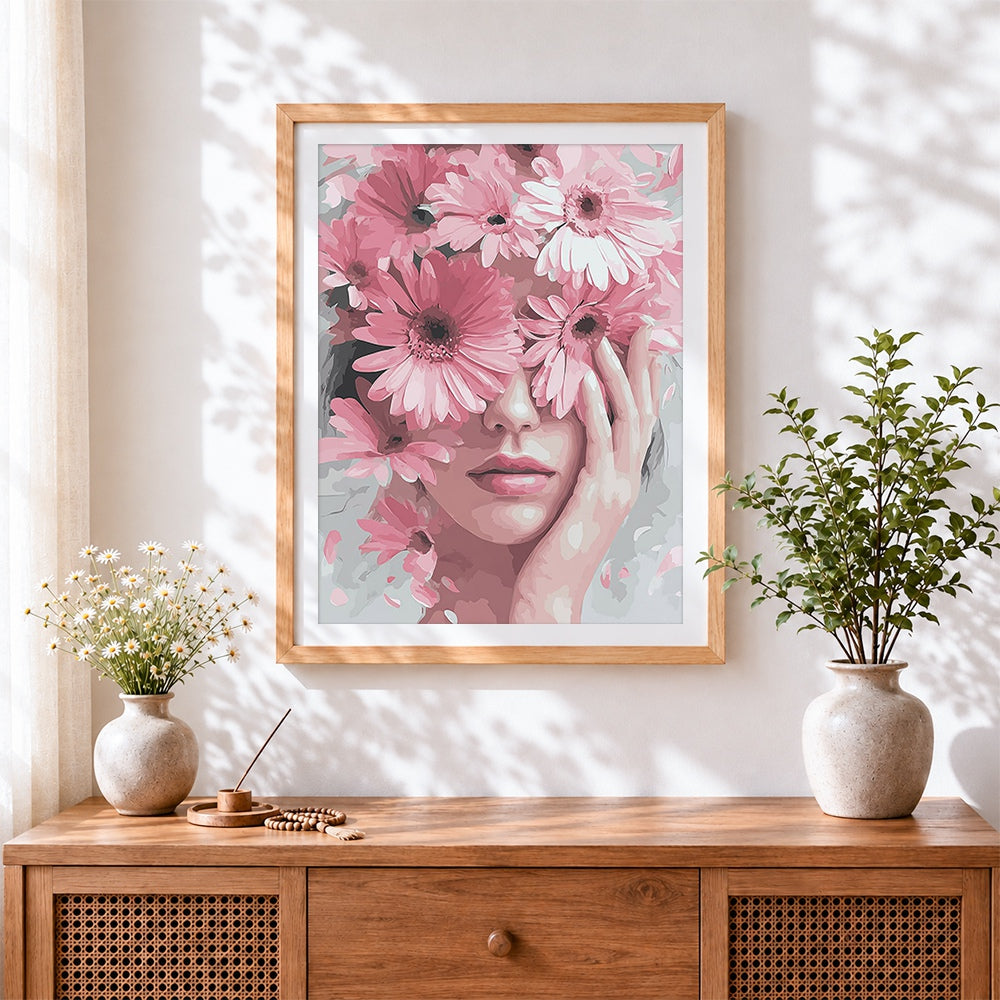 Finished woman holding pink gerbera daisies cross stitch artwork displayed
